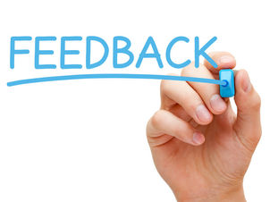 Hand schreibt mit blauem Edding das Wort Feedback