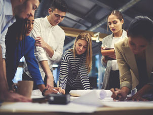 Team arbeitet gemeinsam an Unterlagen – Vertrauen im Team aufbauen im Führungsalltag