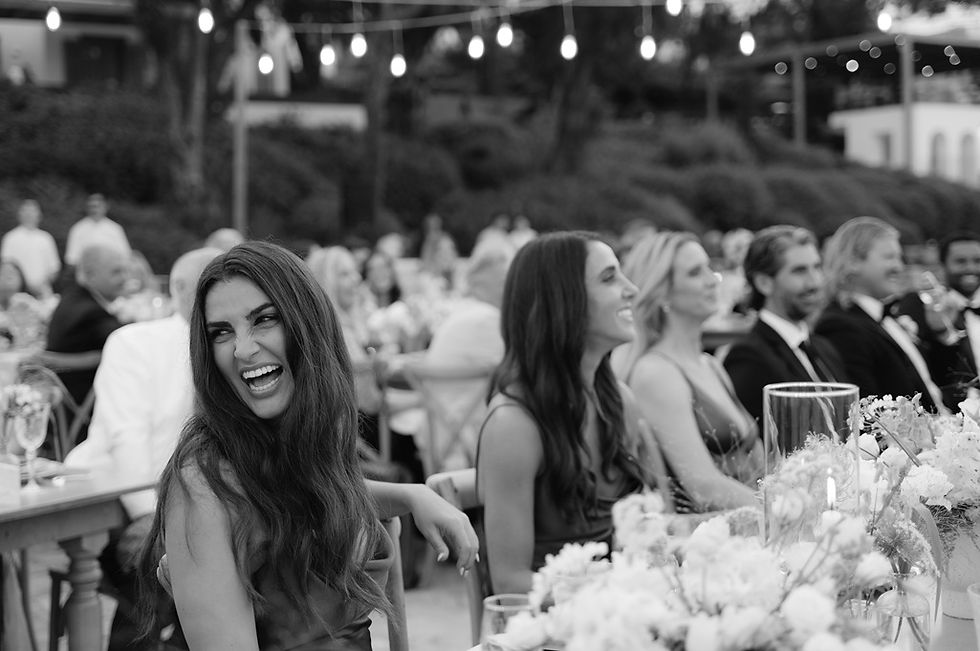 Indian bride & groom dance joyfully on stage in colorful traditional attire at their Indian destination wedding in Crete. Background shows trees, lights, and festive decorations.