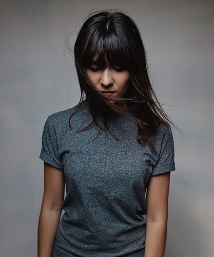 Portrait einer Frau, leichter Blick nach unten, Unsichere Haltung. Sie wirkt sehr klein