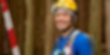 Portrait photo of a local forester wearing his work equipment, smiling at the camera, with trees in the background.