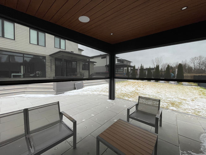 Covered outdoor room with integrated exterior screens, wood soffit ceiling, and open backyard view in winter