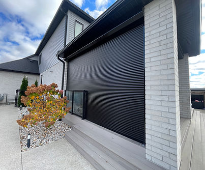 Covered patio at an Ontario lakefront property with exterior roll shutters installed across the open sides for seasonal wind and weather protection