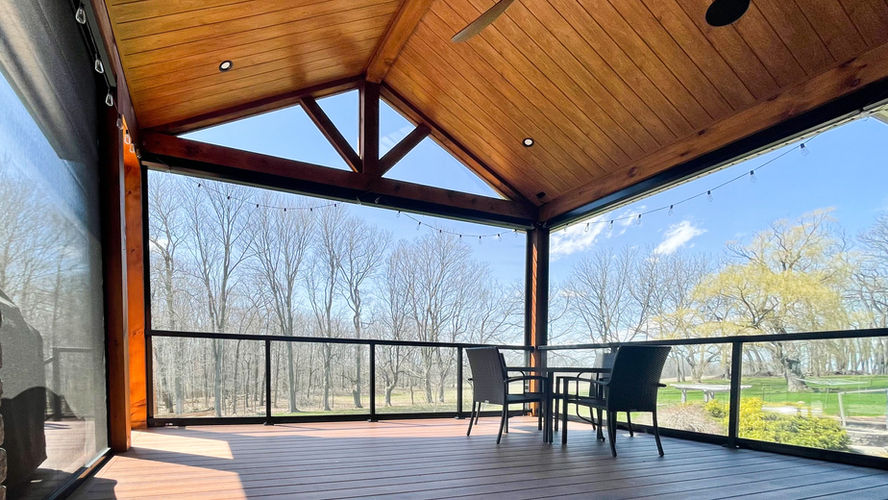 Covered residential patio enclosed with large exterior screens in a landscaped backyard