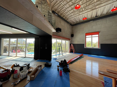Roll shutter installation on large patio door opening in indoor basketball court with pool visible