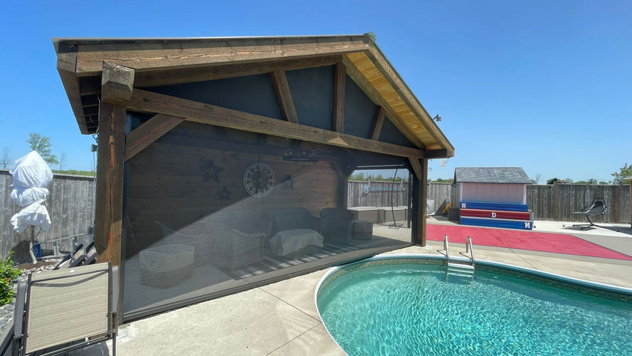 Timber poolside pavilion with a large exterior screen in a residential backyard