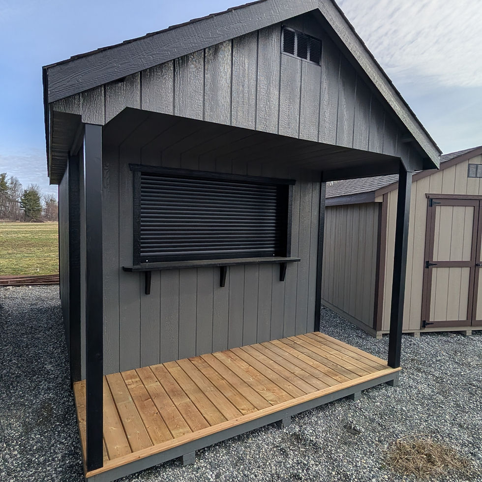 Angled view of a grey cabana bar shed with a black roll-up shutter, serving ledge, and covered wood
