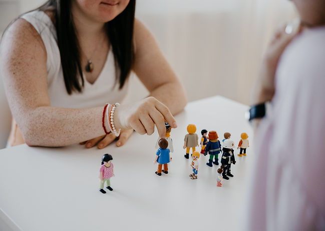 Zwei Personen an einem Tisch. Zwischen ihnen Playmobil-Figuren.