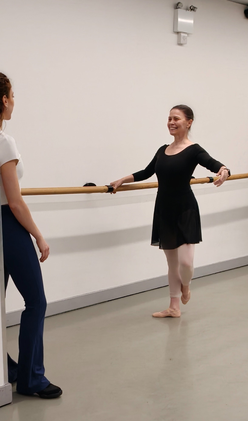 Ballet teacher Ana smiling and guiding an adult beginner student during a barre exercise at Ana en Pointe, London