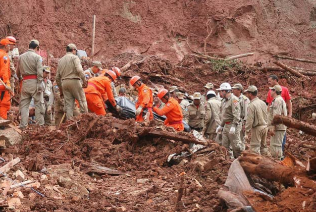 Grupo e bombeiros fazendo buscas por pessoas desaparecidas após um deslizamento de terra.