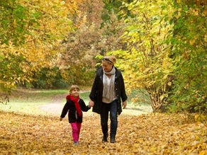 Mother and child walking through autumn woodland