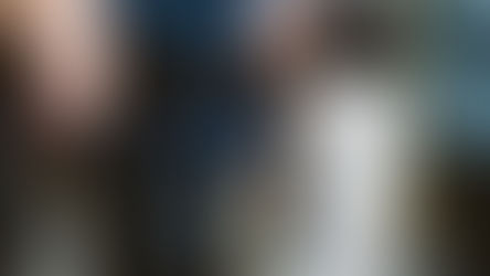 Close-up of a person holding rosary beads and a paper during an outdoor prayer gathering, with others blurred in background.