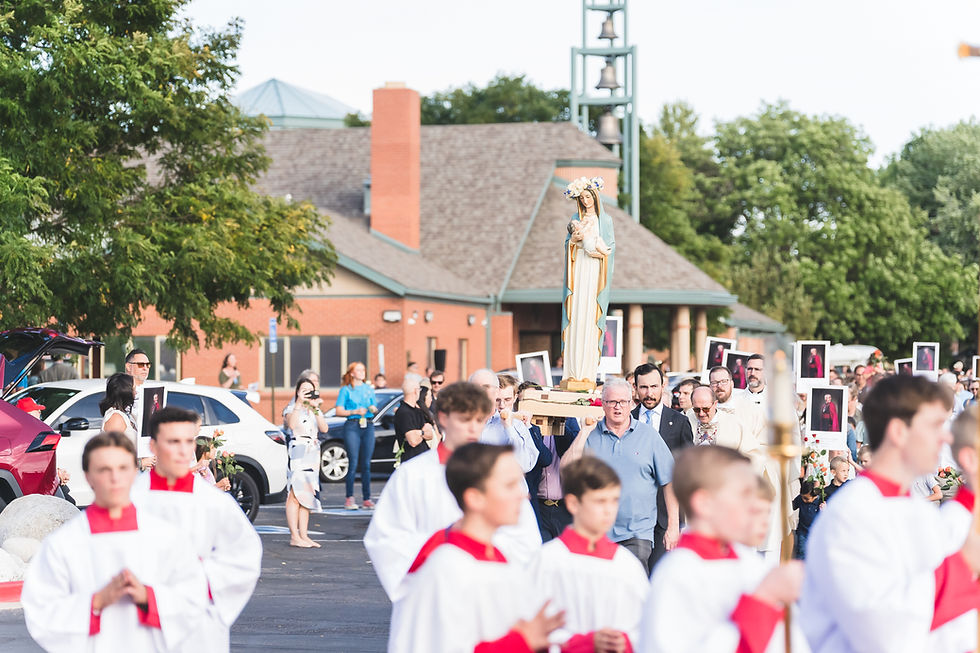 Catholic procession with men carrying a Mary statue, altar servers in white and red, and a crowd outside a church on a sunny day