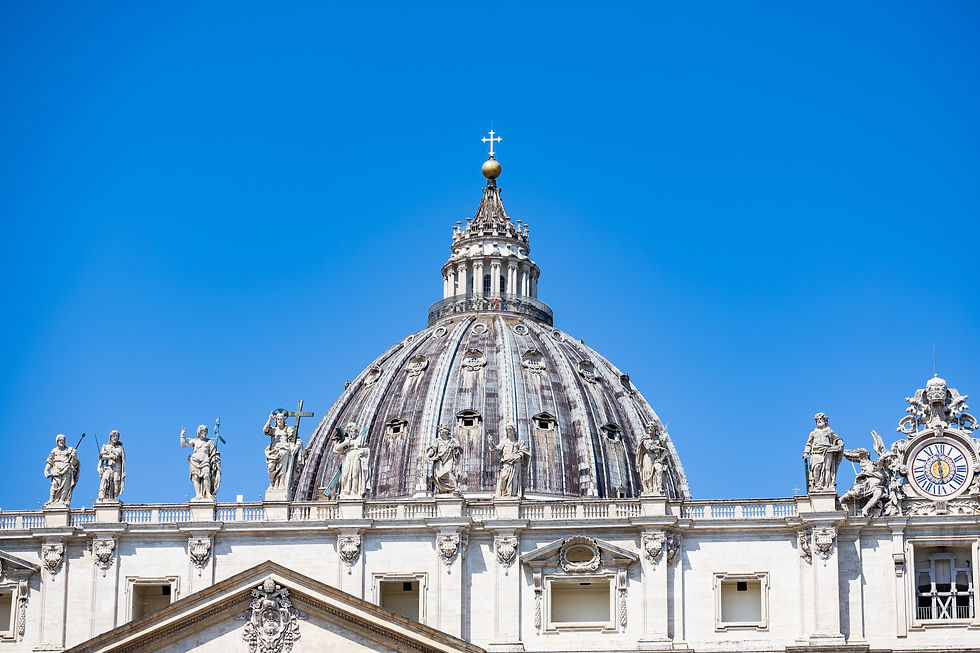 St. Peter’s Basilica dome and statues against a clear blue sky, with a clock on the right and no people visible.