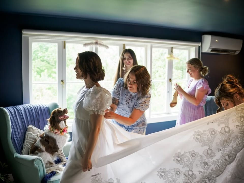 Molly and her bridal party sharing a moment before the ceremony. Light streaming through the window highlighting the lace detail on the dress