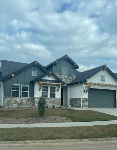 Exterior view of a modern house, cloudy sky, with stone and wood accents.