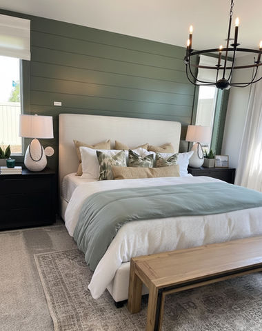 Bedroom with bed, pillows, lamps, and bench. Green wall with bright window.
