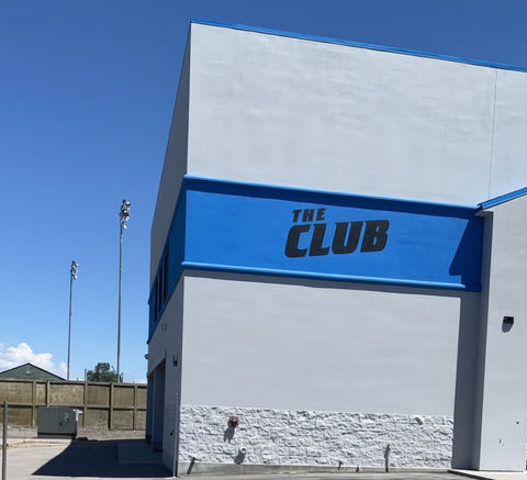 Building with "THE CLUB" sign in bright daylight, clear sky background.