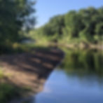 Tree-lined river flowing through Cambridge City Park in Cambridge, Minnesota