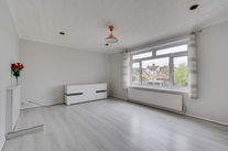 Empty room with large window and minimal furniture.