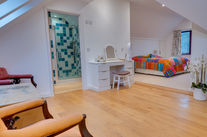 Bright bedroom with colorful bedspread and wooden floor.