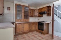 Wooden kitchen cabinets with glass doors and tiled floor.