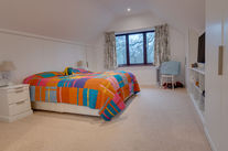 Bedroom with colorful bedspread and large window.