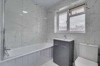 Modern bathroom with marble walls and sleek fixtures.