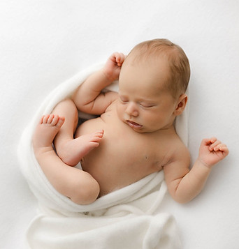 Newborn baby curled up asleep.