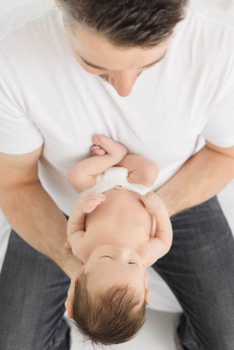 Father looking down at newborn in hands.