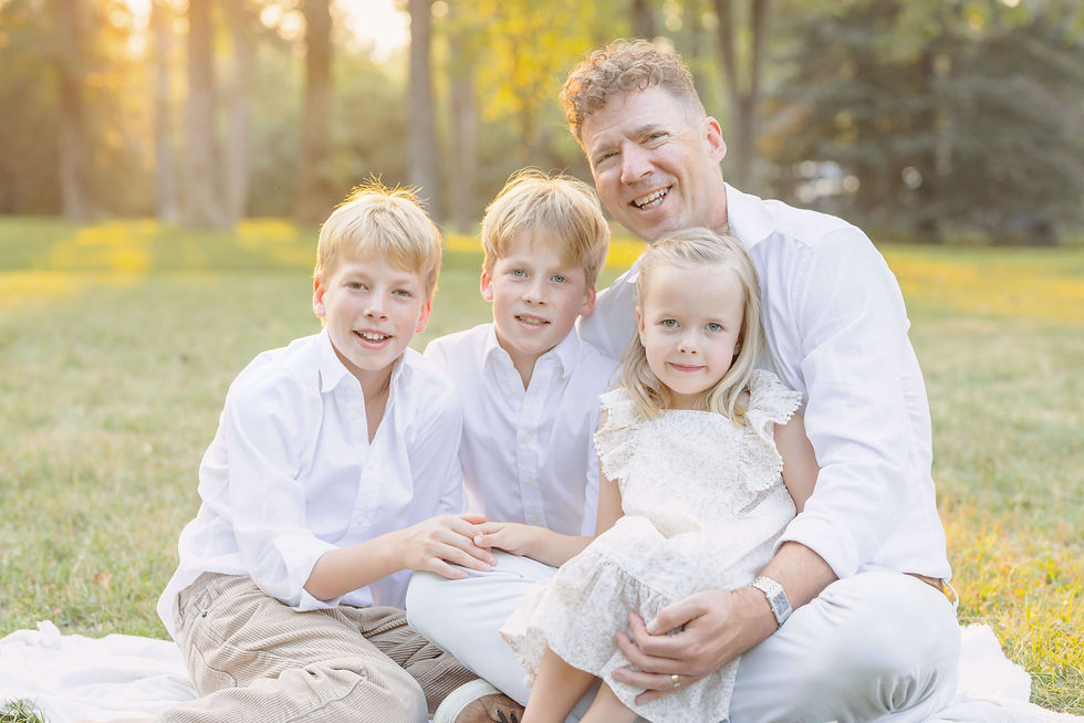 Father poses with three children in field.