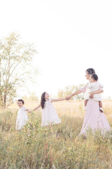 Mother leading daughters through grass