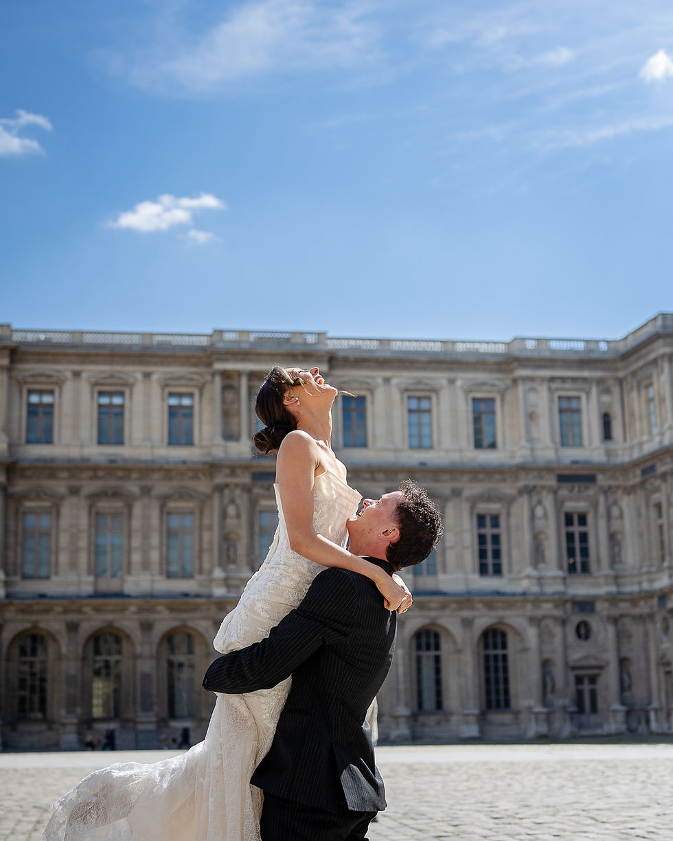 An embrace full of laughter as a wedding couple spin in the sun surrounded by the Cour Carrée