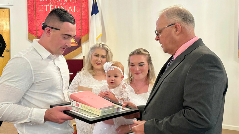 person handing baby dedication certificate to parent