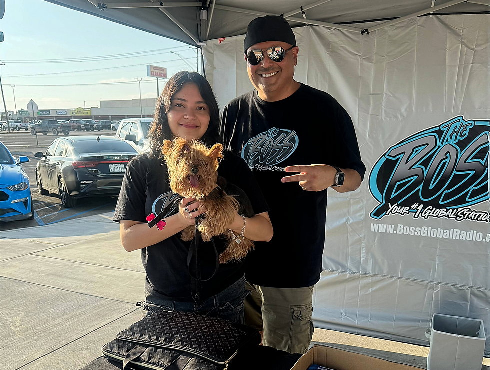The BEAT Boss and his daughter standing together at a Boss Global Radio event, smiling under the station tent with their small dog in her arms.