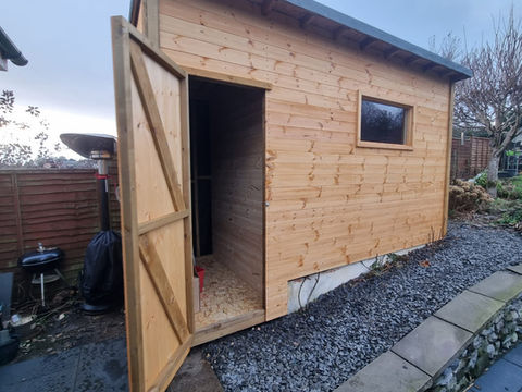 Open door view of timber workshop shed in Barrow-in-Furness with horizontal cladding and fixed window