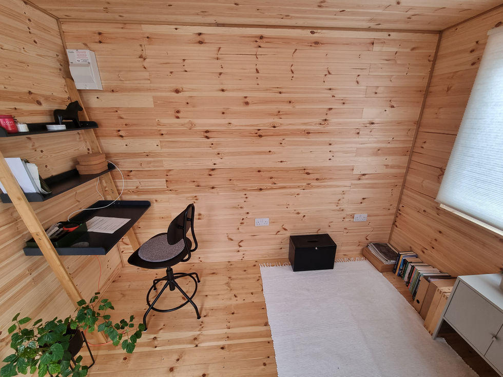 Minimalist home office interior in timber garden room with desk, shelving, and rug on wood floor