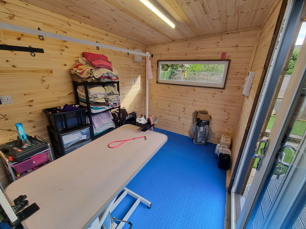 Professional dog grooming workspace with grooming table, shelving and pine wood walls