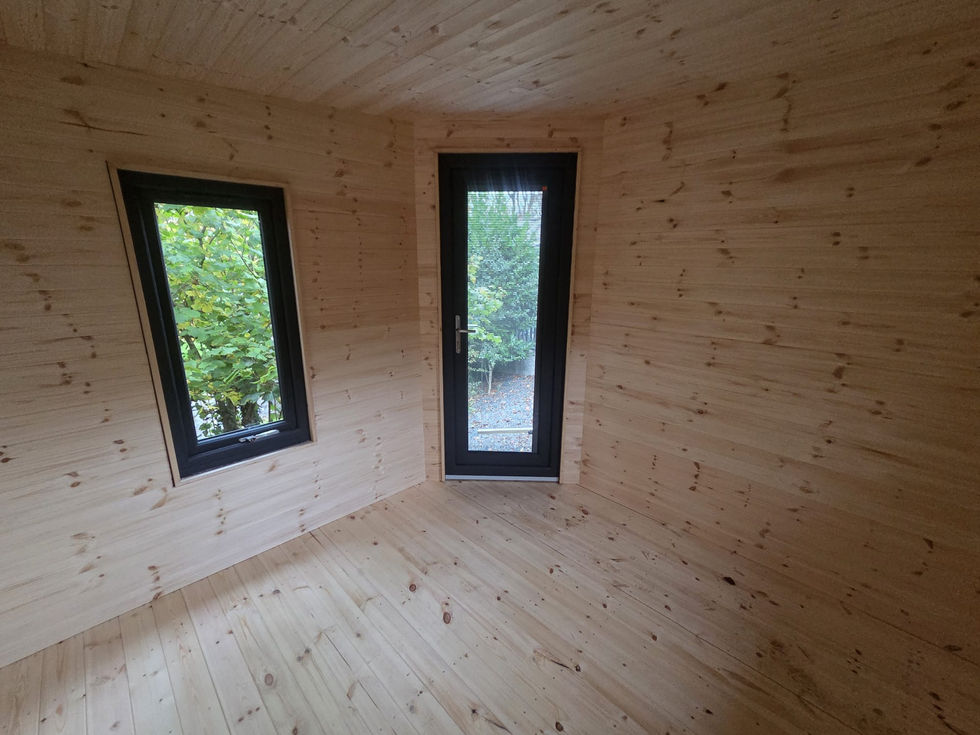 Empty timber-lined garden room interior with side window and glazed diagonal corner door, Cumbria