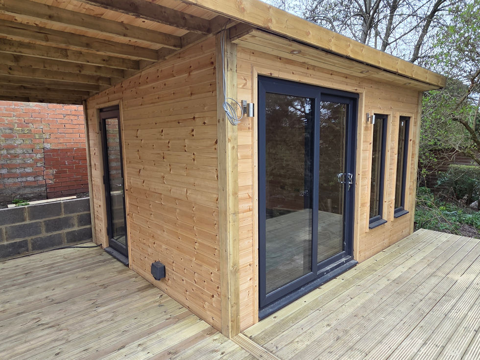 Modern timber garden room with black-framed French doors and tall vertical windows, set on raised decking with covered canopy