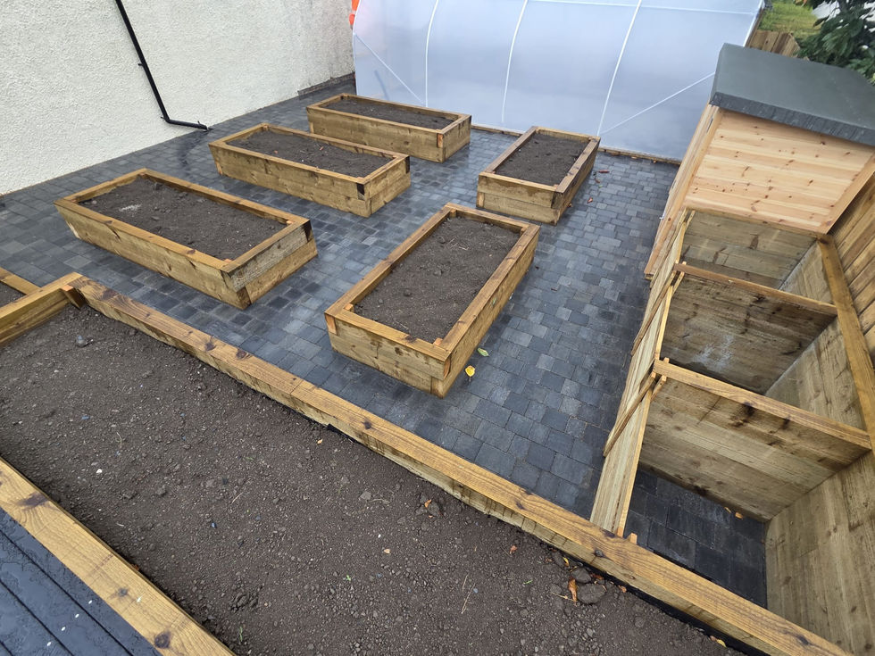 Timber sleeper raised beds on charcoal block paving with a growing polytunnel behind, Cumbria