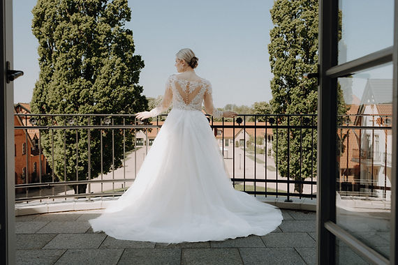 Elegante Braut in Prinzessinnenkleid auf Balkon