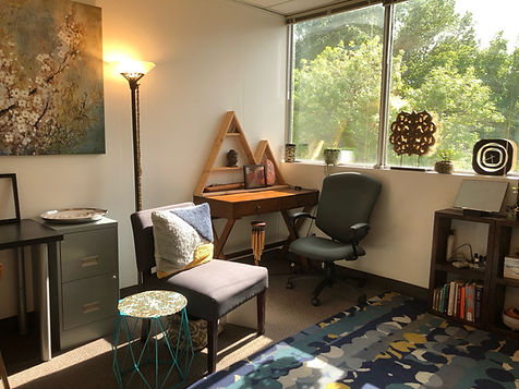Window office with view of trees wood desk lamp chair
