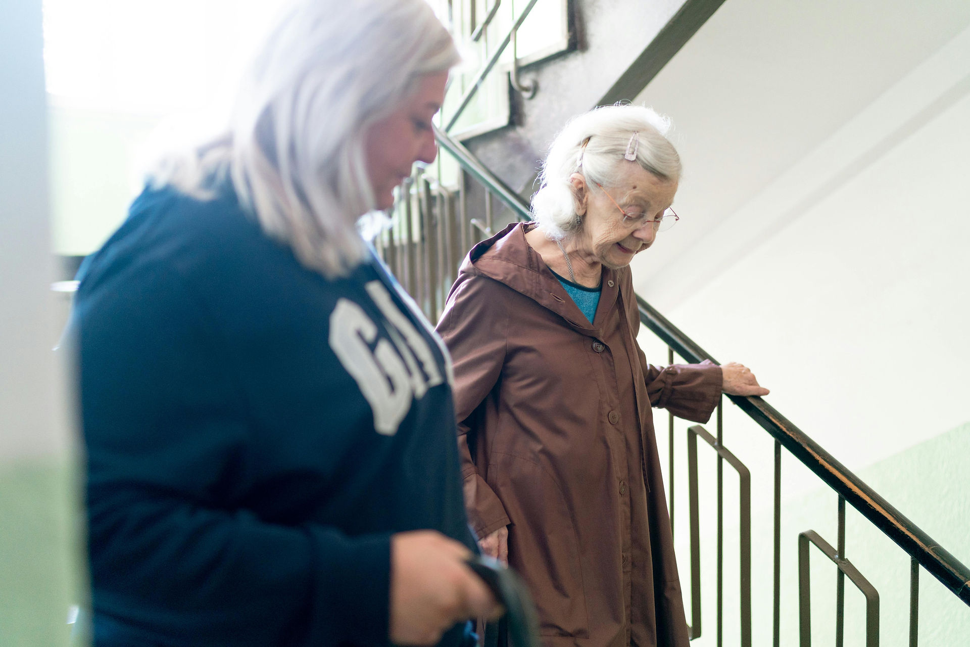 Pflegekraft hilft Seniorin beim sicheren Treppensteigen – Unterstützung im Alltag zuhause.