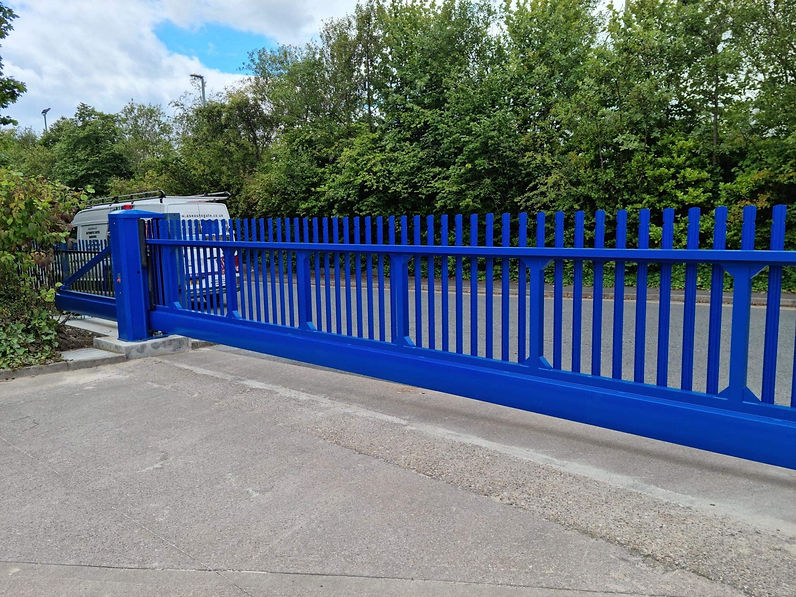 A large blue metal gate spans across a concrete driveway