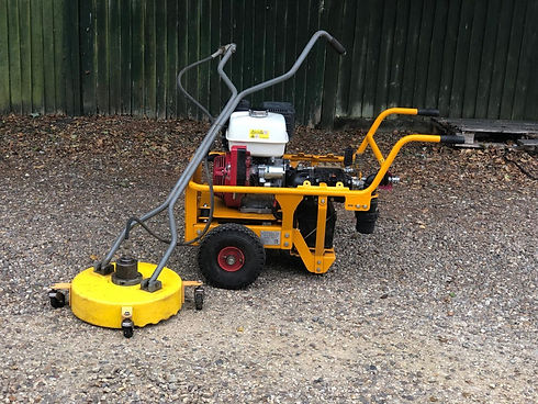 Yellow petrol-powered pressure washer surface cleaner machine on gravel