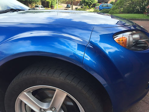 High gloss finish on a blue car front wheel arch after expert mobile paint restoration