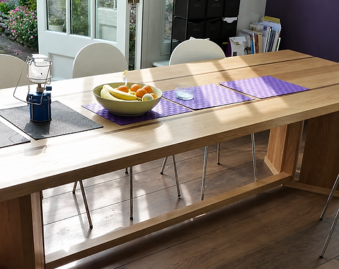 Long bespoke wooden dining table set with runner in sunlit dining area