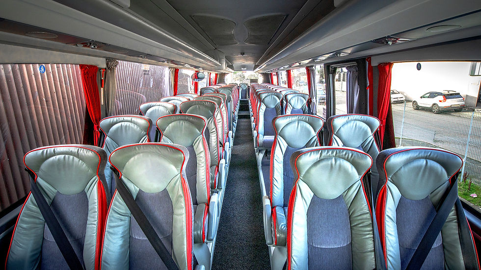 Interior of an empty bus with two rows of plush, grey and red seats, seatbelts visible