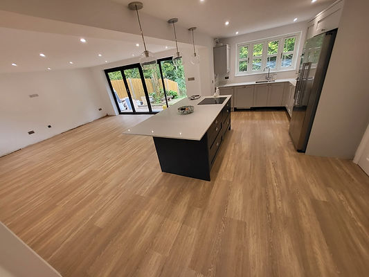 Light wood tone luxury vinyl flooring fitted in a spacious modern open plan kitchen with an island